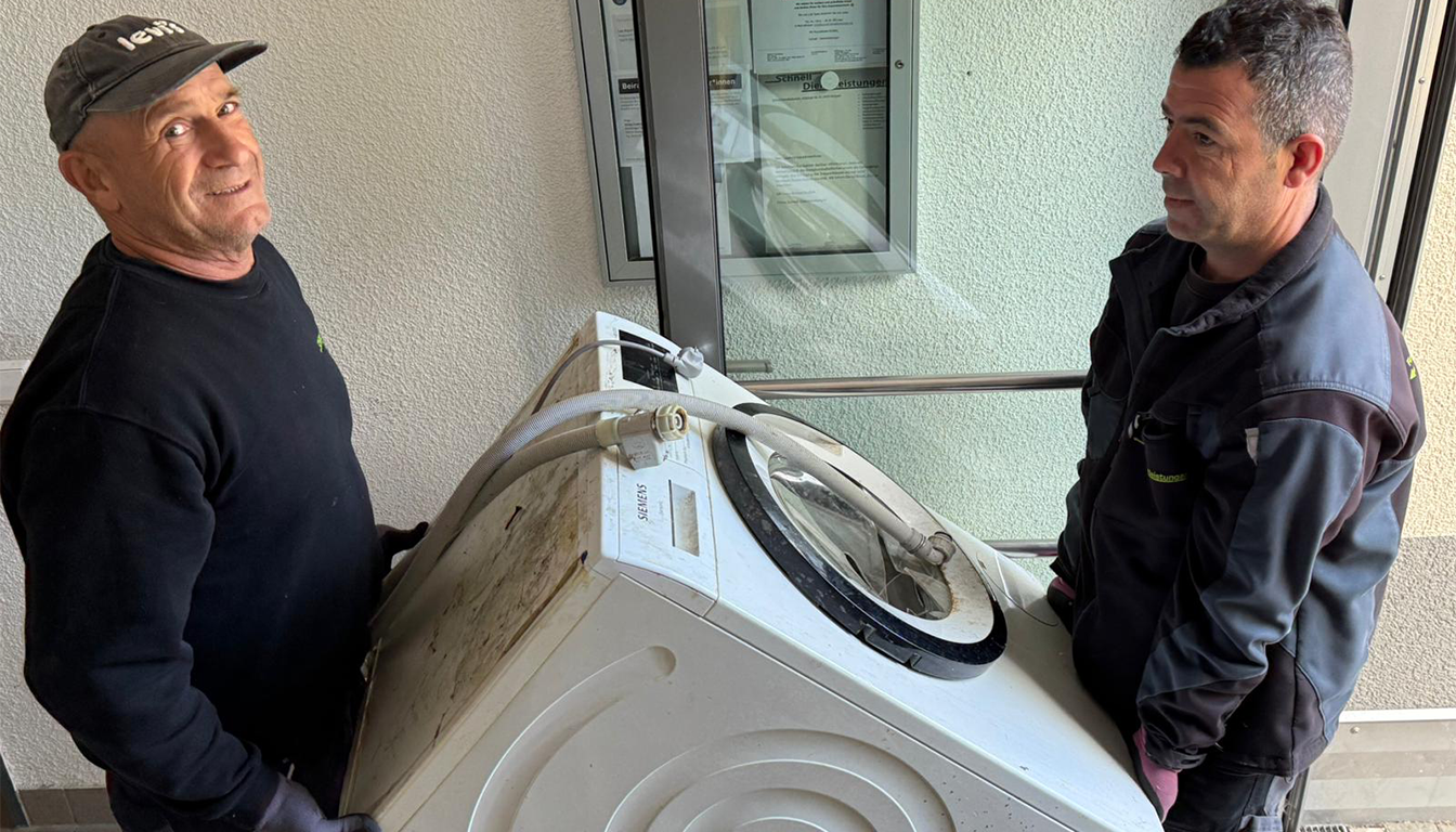 Entsorgung in Stuttgart – zwei Mitarbeiter von Schnell Dienstleistungen tragen eine Waschmaschine aus einer Wohnung